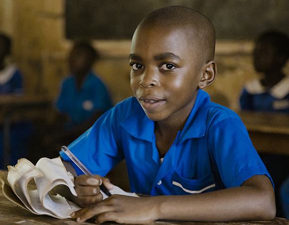 Young school boy writes in his journal in a classroom.